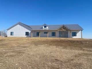 a large white house with a metal roof is sitting on top of a dry grass field