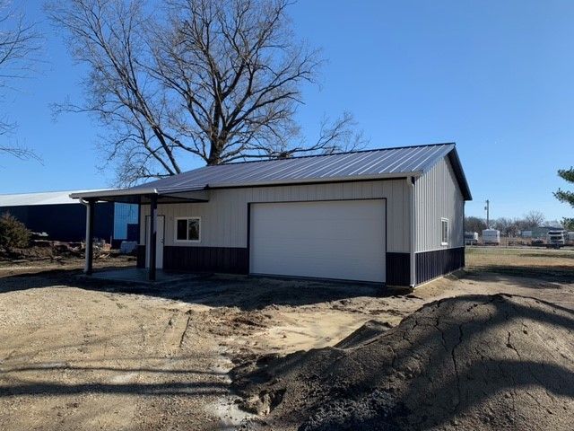 a garage with a porch and a tree in the background