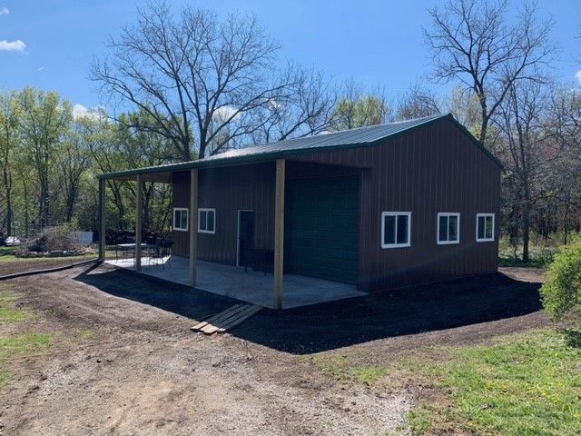 a brown metal building with a green roof and a porch