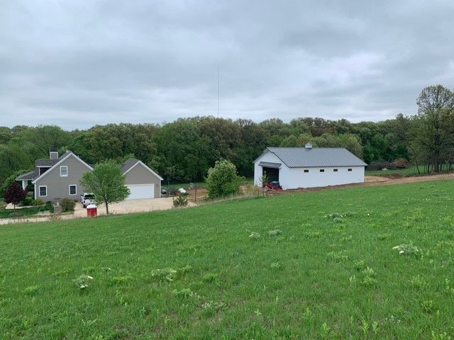 there is a house and a barn in the middle of a grassy field