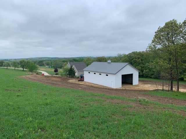 a white barn is sitting in the middle of a grassy field