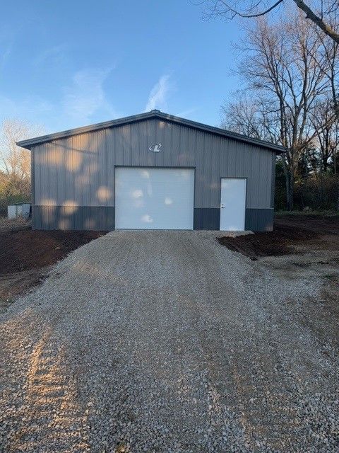a garage with a white door and a gravel driveway leading to it