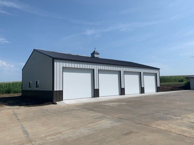 a large metal building with four garage doors is sitting on top of a dirt field
