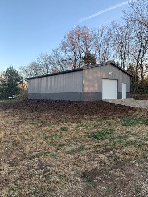 a large metal building is sitting in the middle of a field