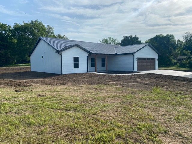 a white house with a gray roof is sitting in the middle of a grassy field