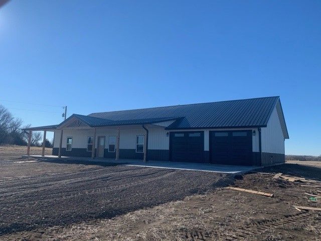 a white house with a black garage door and a porch