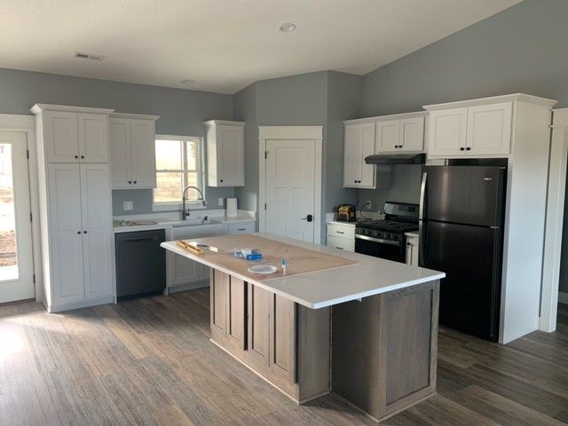 a kitchen with white cabinets and a black refrigerator