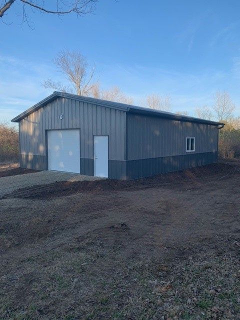 a large metal building is sitting in the middle of a dirt field