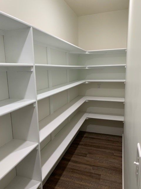 a closet with lots of shelves and a wooden floor