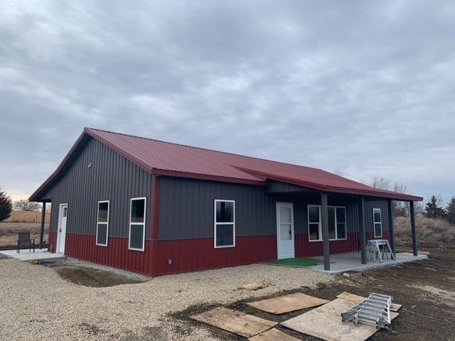 a red and black building with a porch and a ladder in front of it