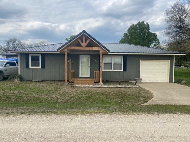 a gray house with a metal roof and a white garage door