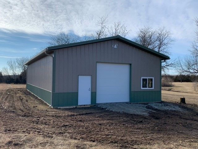 a large metal building is sitting in the middle of a dirt field