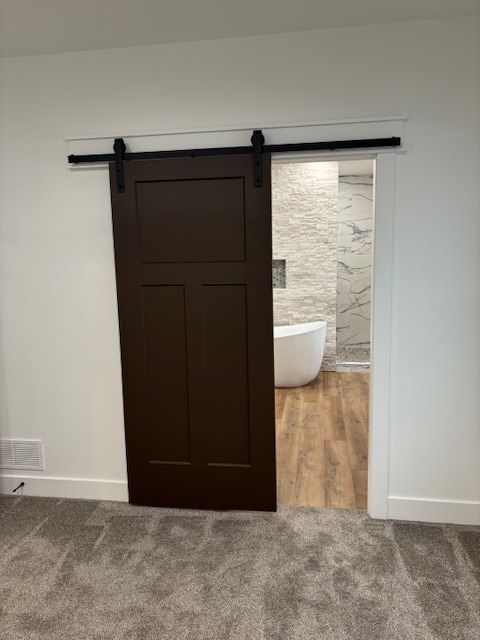 a bedroom with a sliding barn door leading to a bathroom