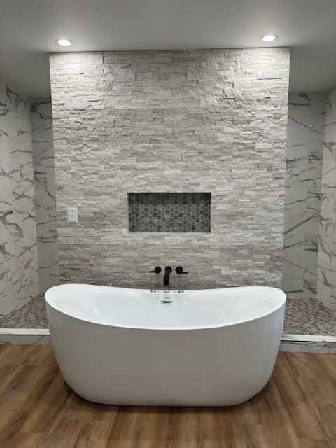 a bathtub is sitting in a bathroom next to a marble wall