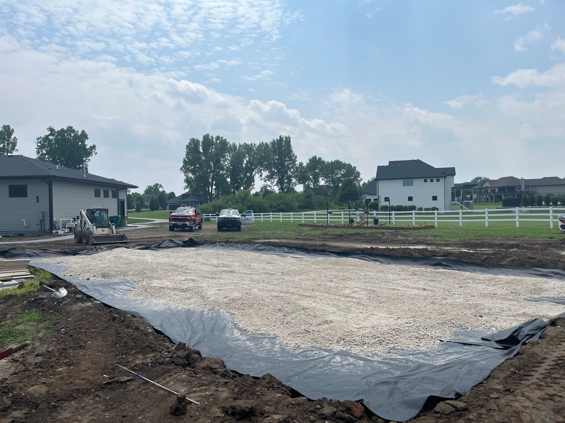 A construction site with a lot of dirt and a house in the background.