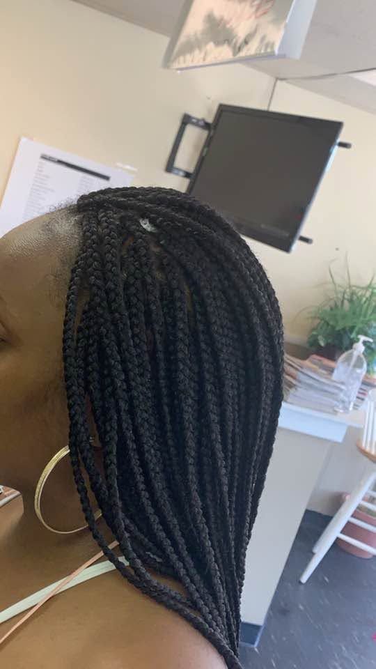 Braided hairstyle in profile indoors, with hoop earring and a TV in the background.
