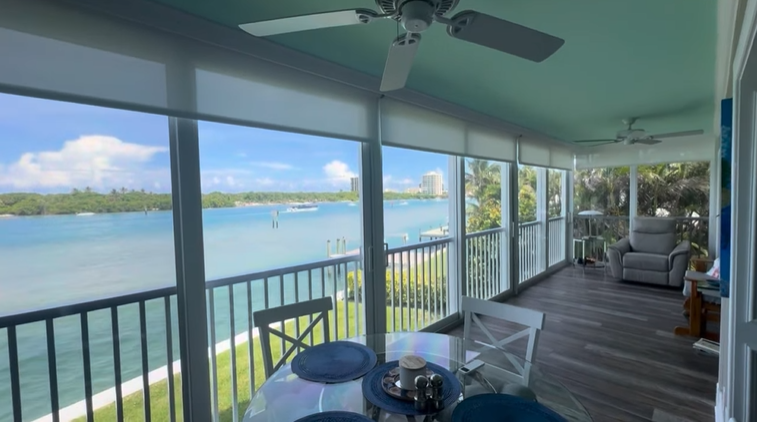 Sunroom overlooking a waterway with white and blue furnishings.
