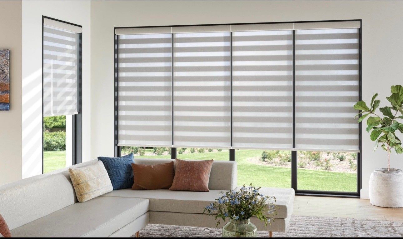 Living room with sectional sofa and banded window shades; green yard visible.