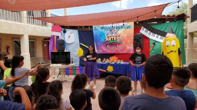 A group of children are standing in front of a stage watching a performance.