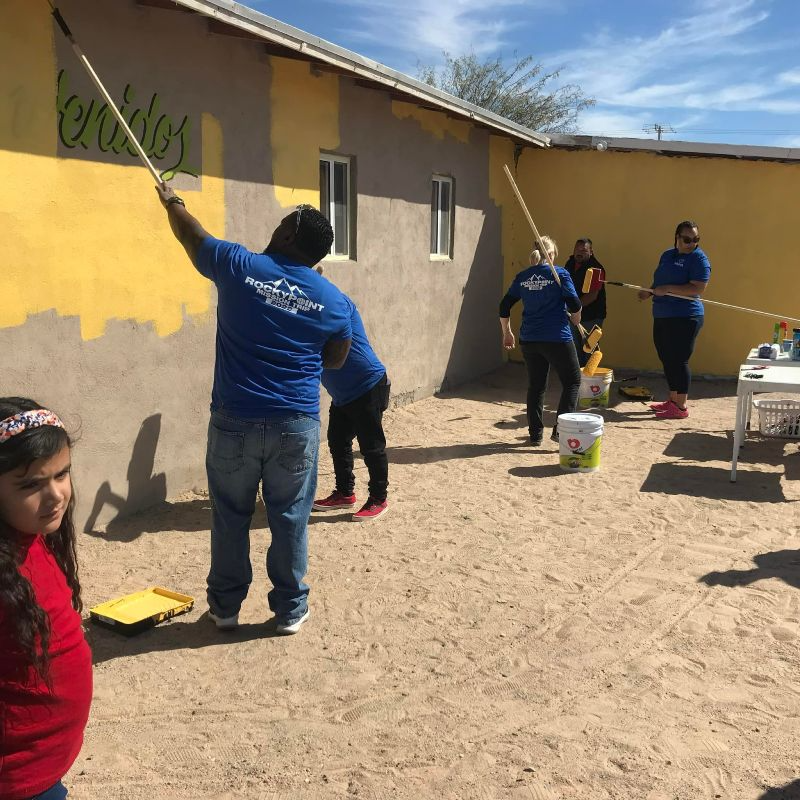 A group of people are painting a wall that says