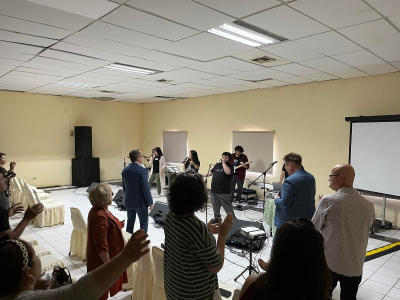 A group of people are standing in a room with their hands in the air.