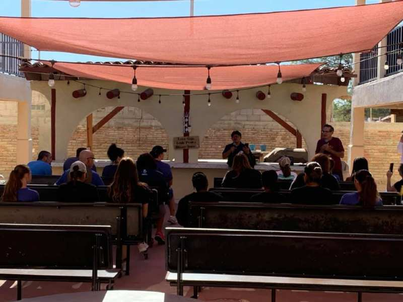 A group of people sitting under a canopy with a sign that says no dogs