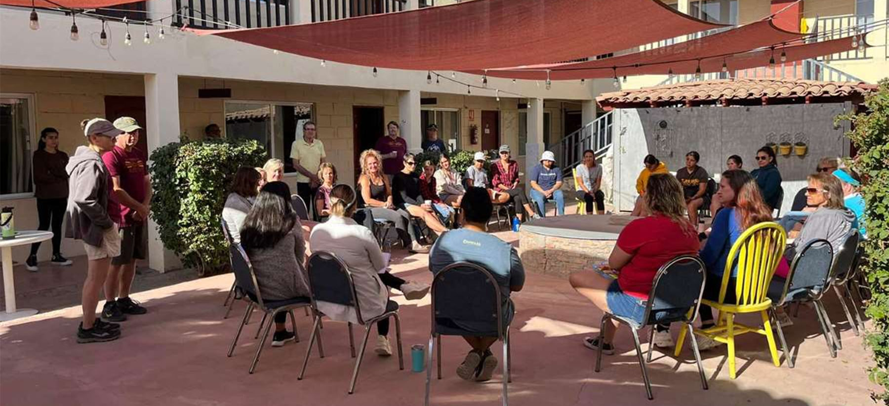 A group of people are sitting in chairs outside of a building.