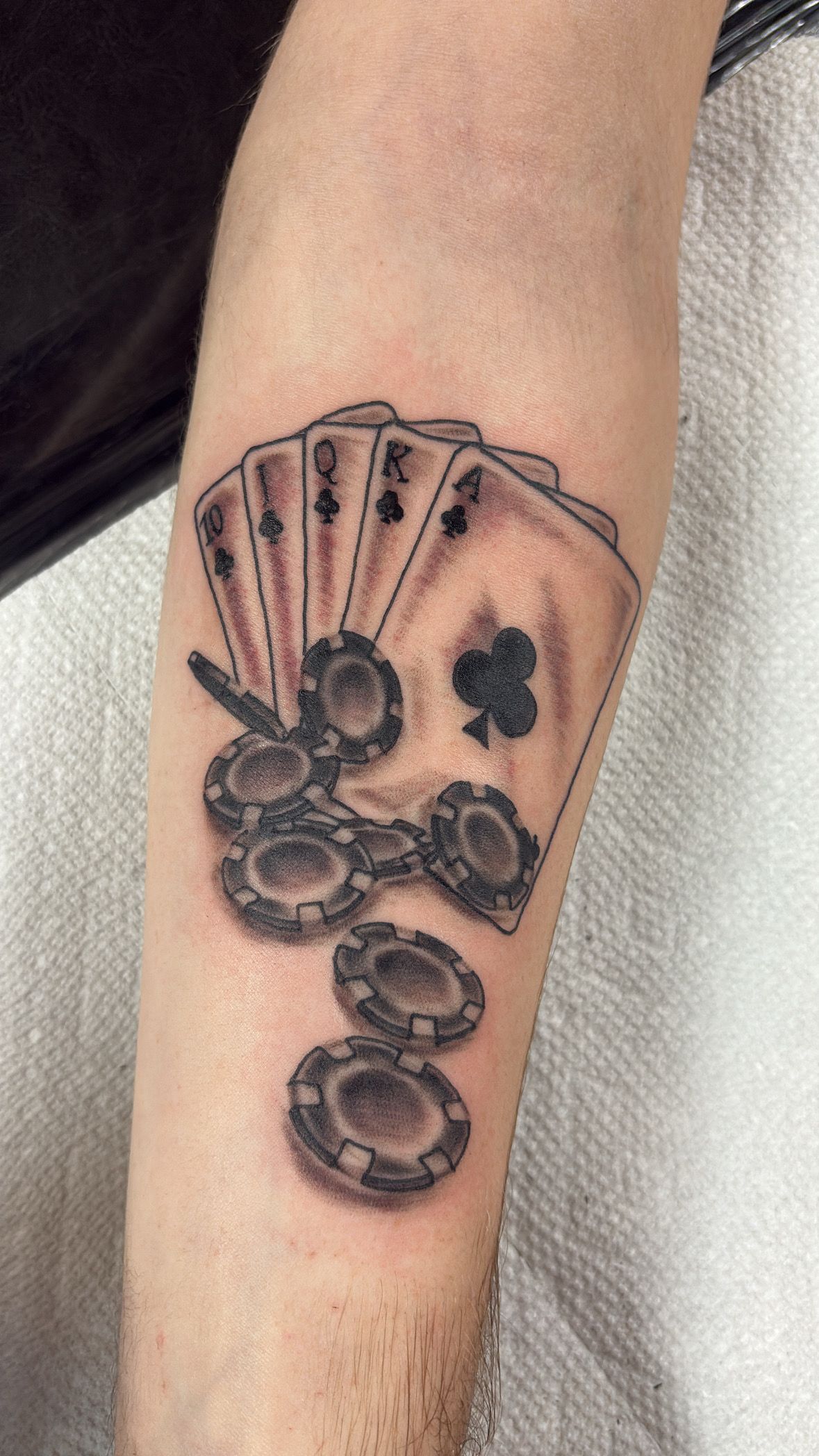 A man has a tattoo of playing cards and poker chips on his arm.