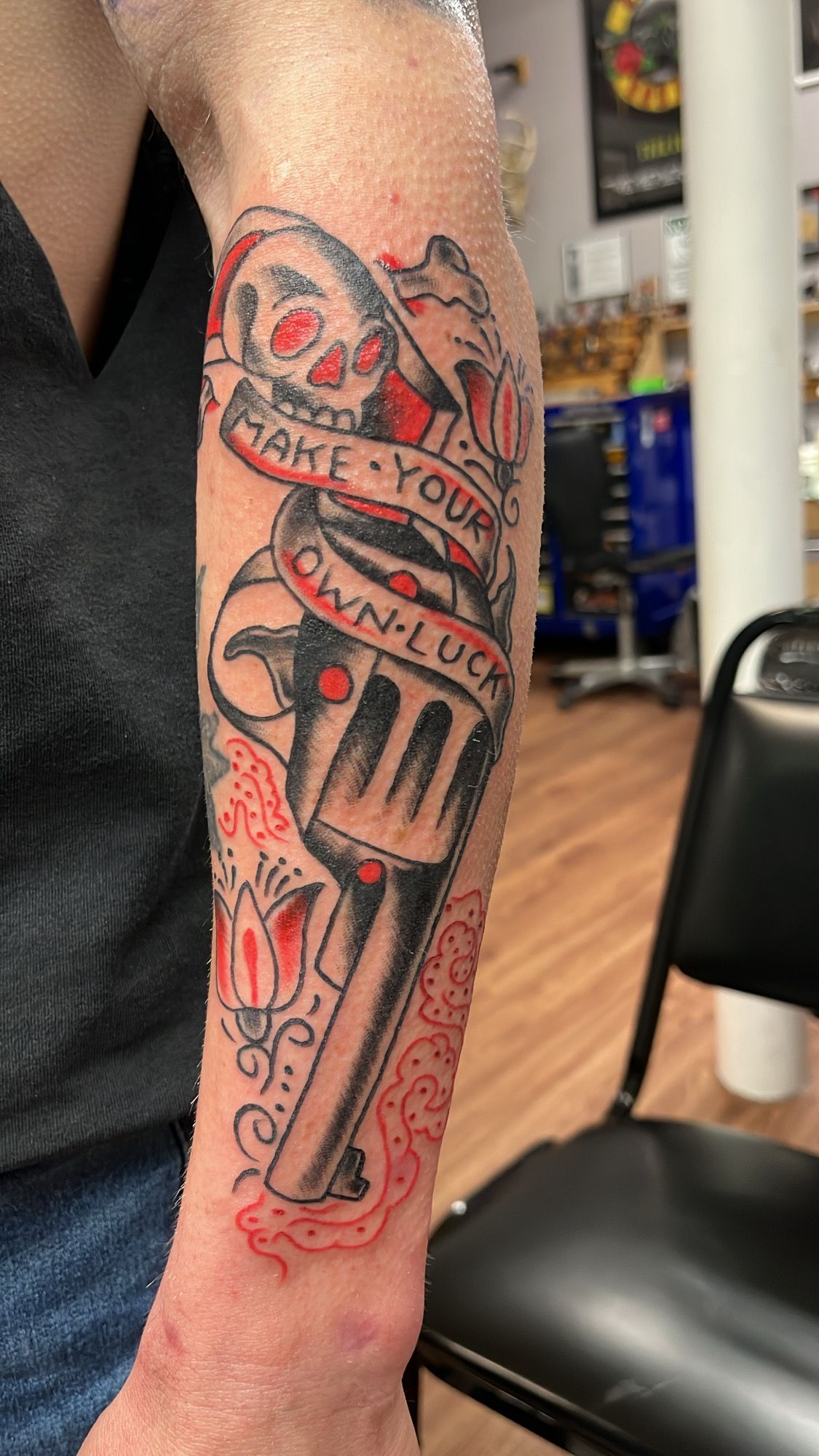 A man has a tattoo of a revolver on his arm.
