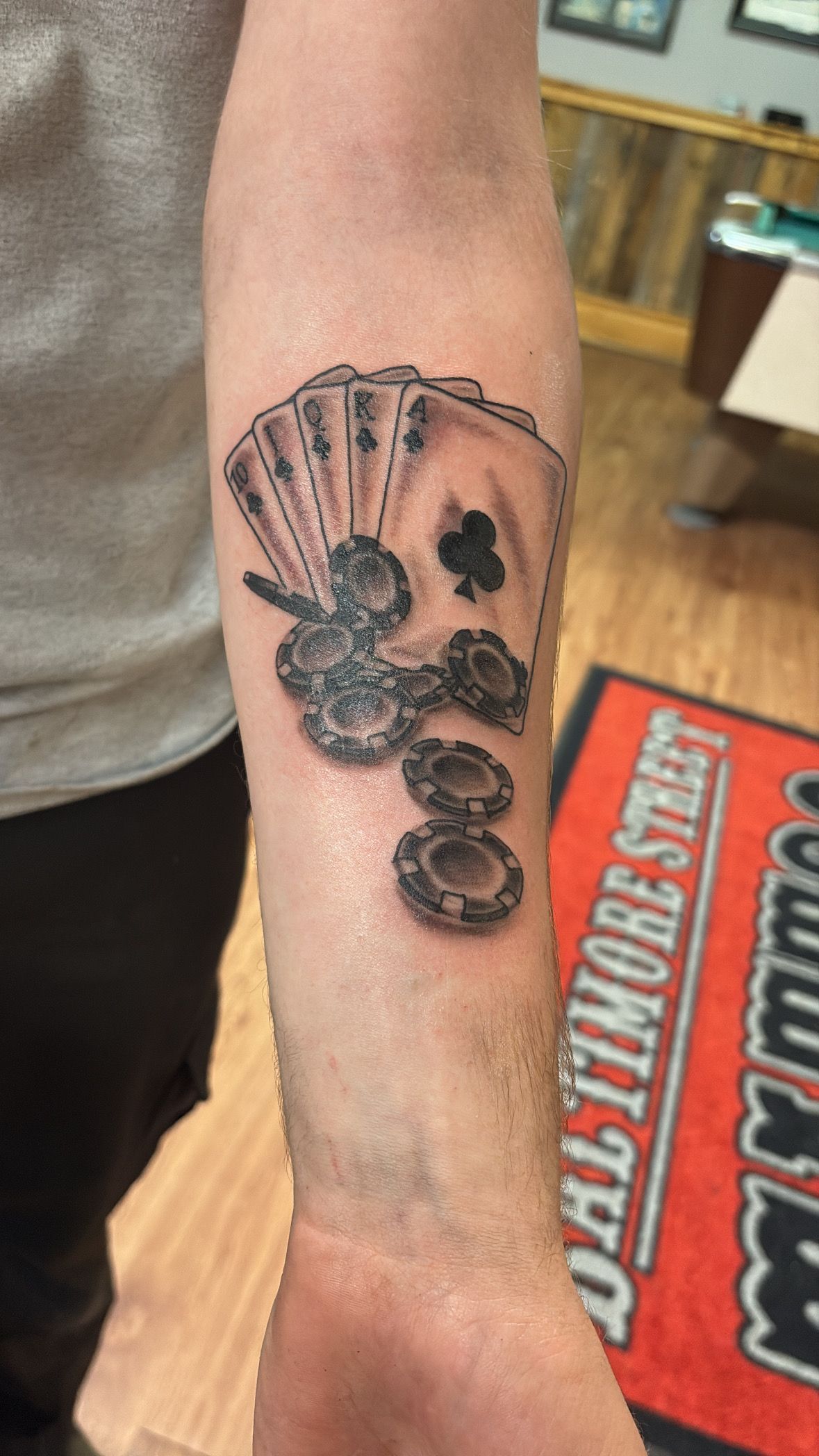 A man has a tattoo of playing cards on his forearm