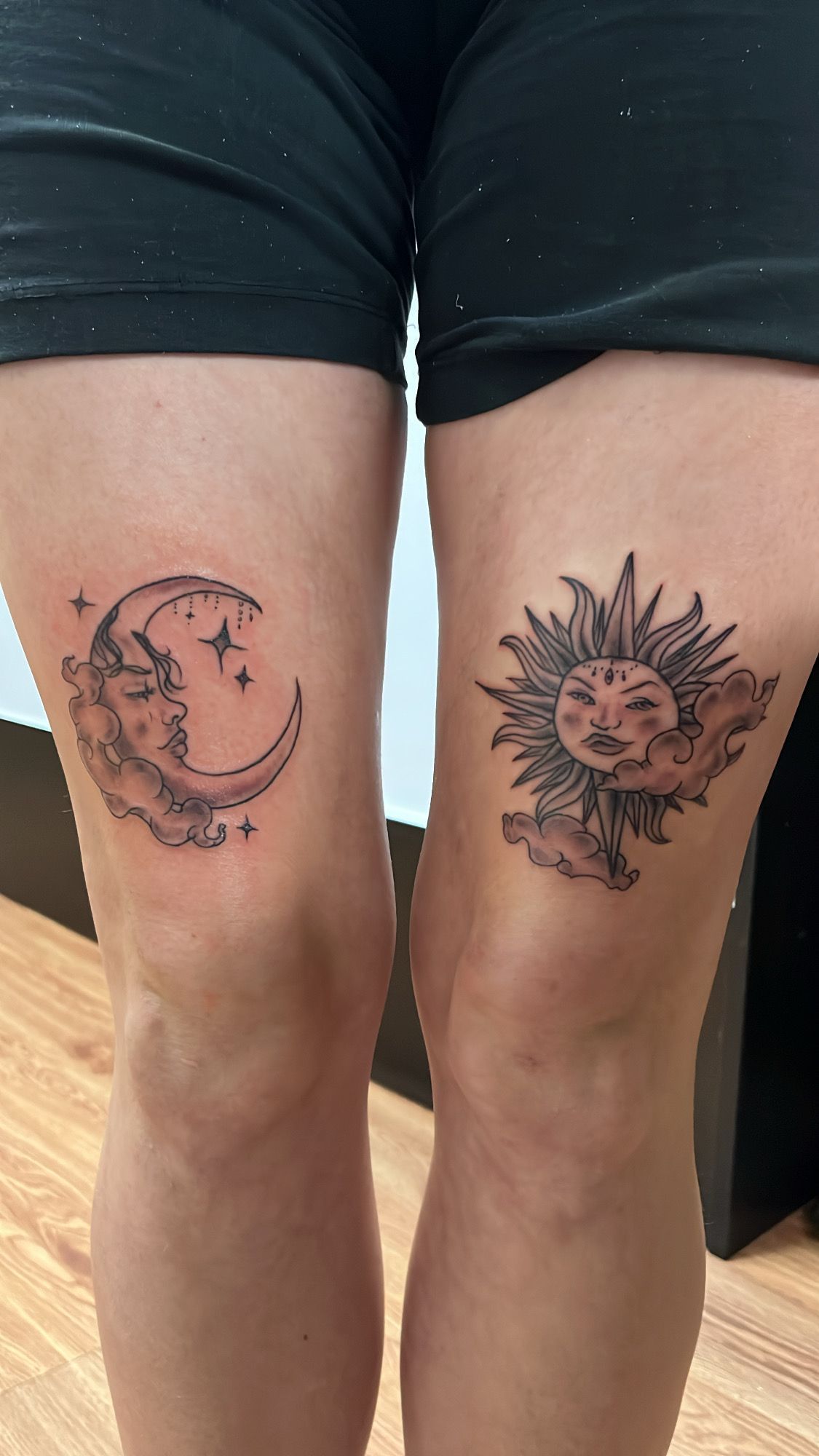 A woman has a crescent moon and a sun tattoo on her thighs.