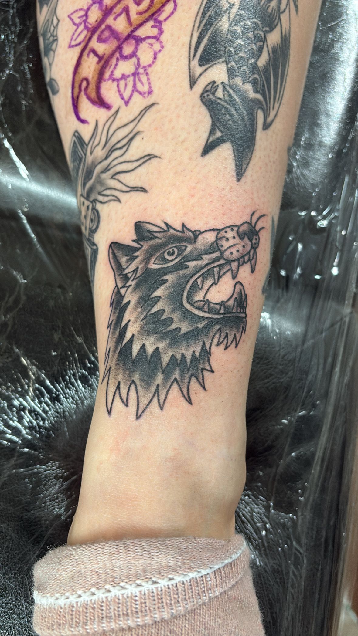 A person has a tattoo of a wolf on their leg.