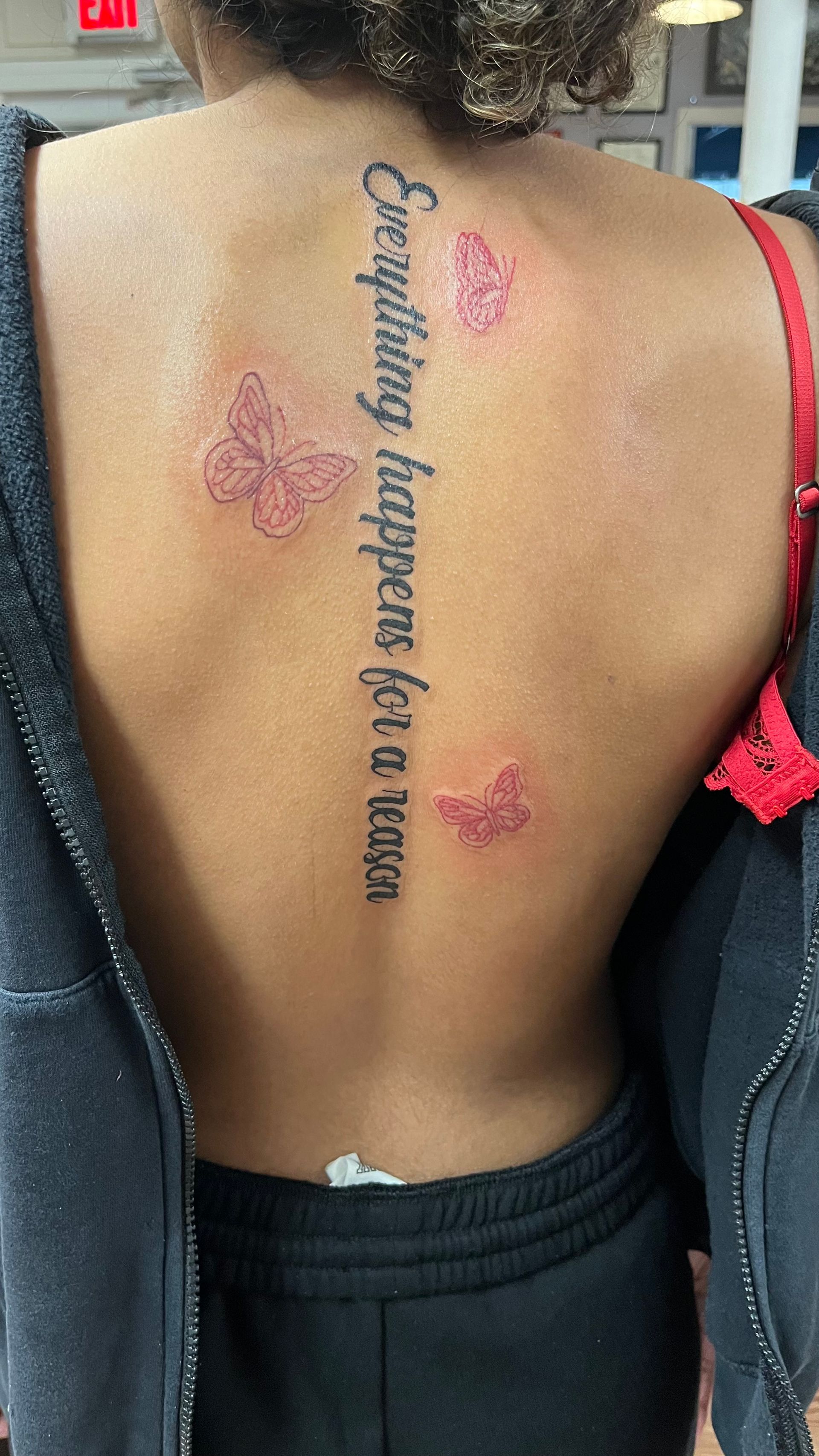 A woman has a tattoo on her back that says everything happens for a reason