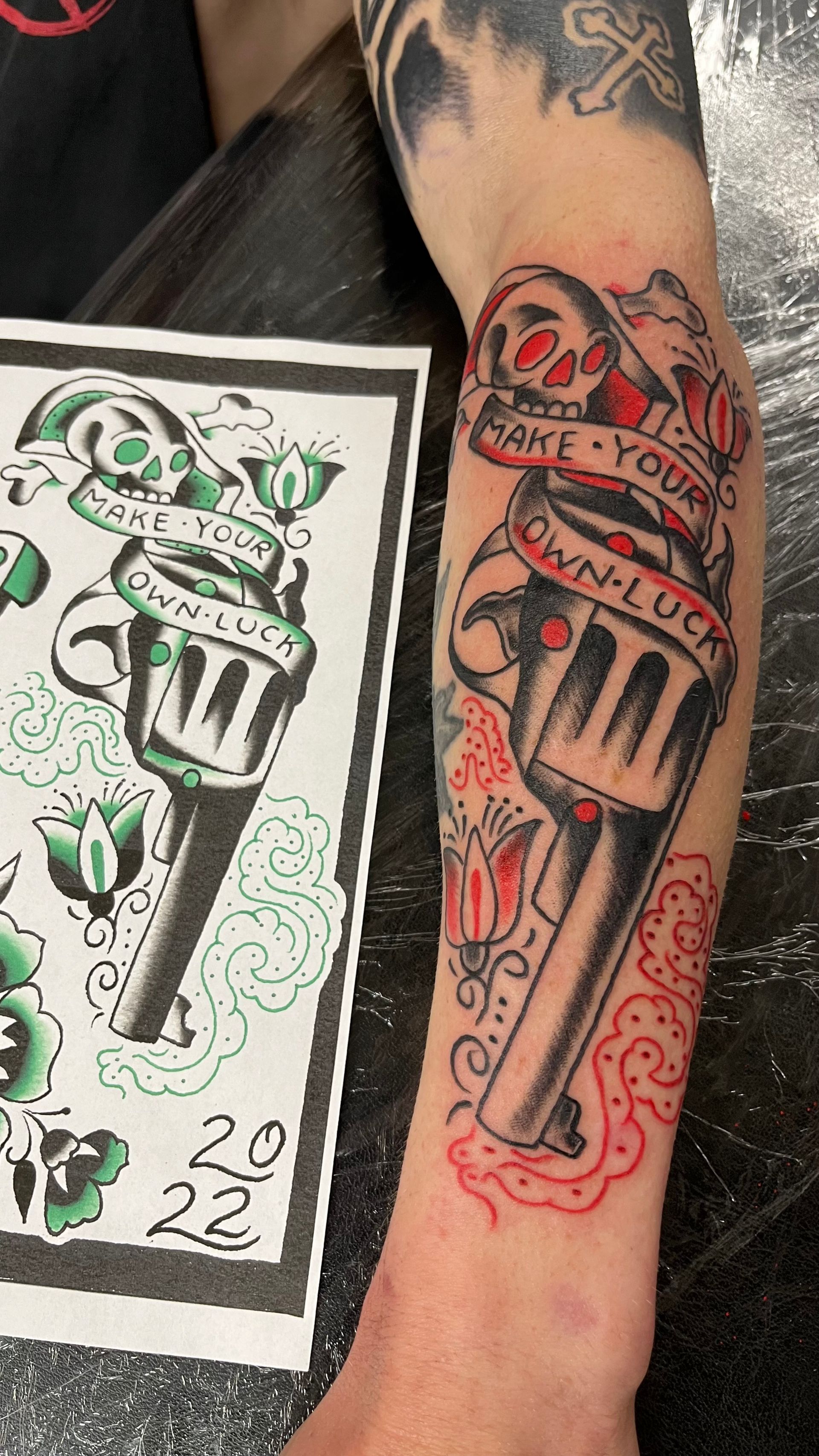 A man has a tattoo of a revolver on his arm.