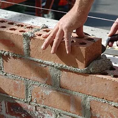 a person is laying bricks on a wall with a trowel