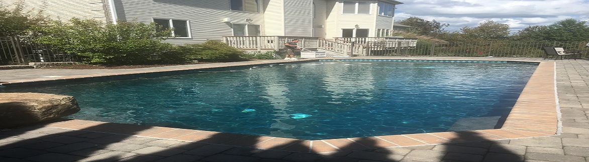 A large swimming pool is in the backyard of a house