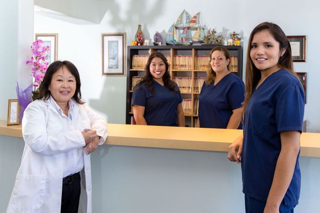 Four staff members stand behind a front desk in a bright office lobby