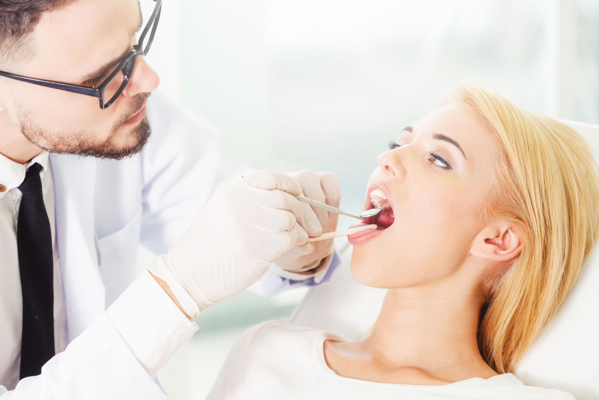 Dentist examining a patient’s mouth with dental tools in a bright clinic