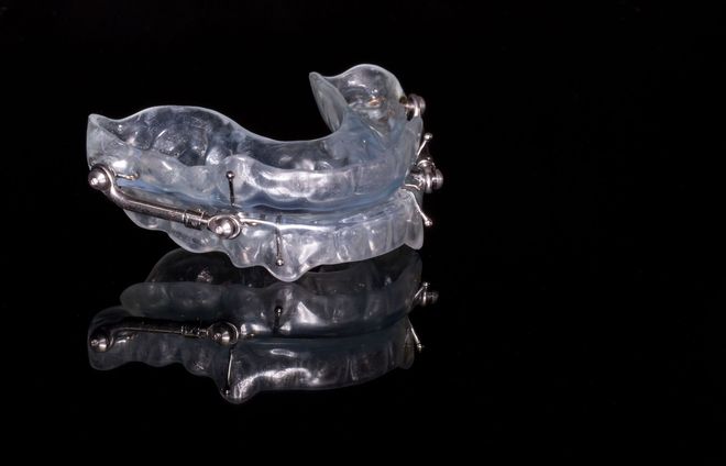 Clear plastic dental mouthguard on a black reflective surface