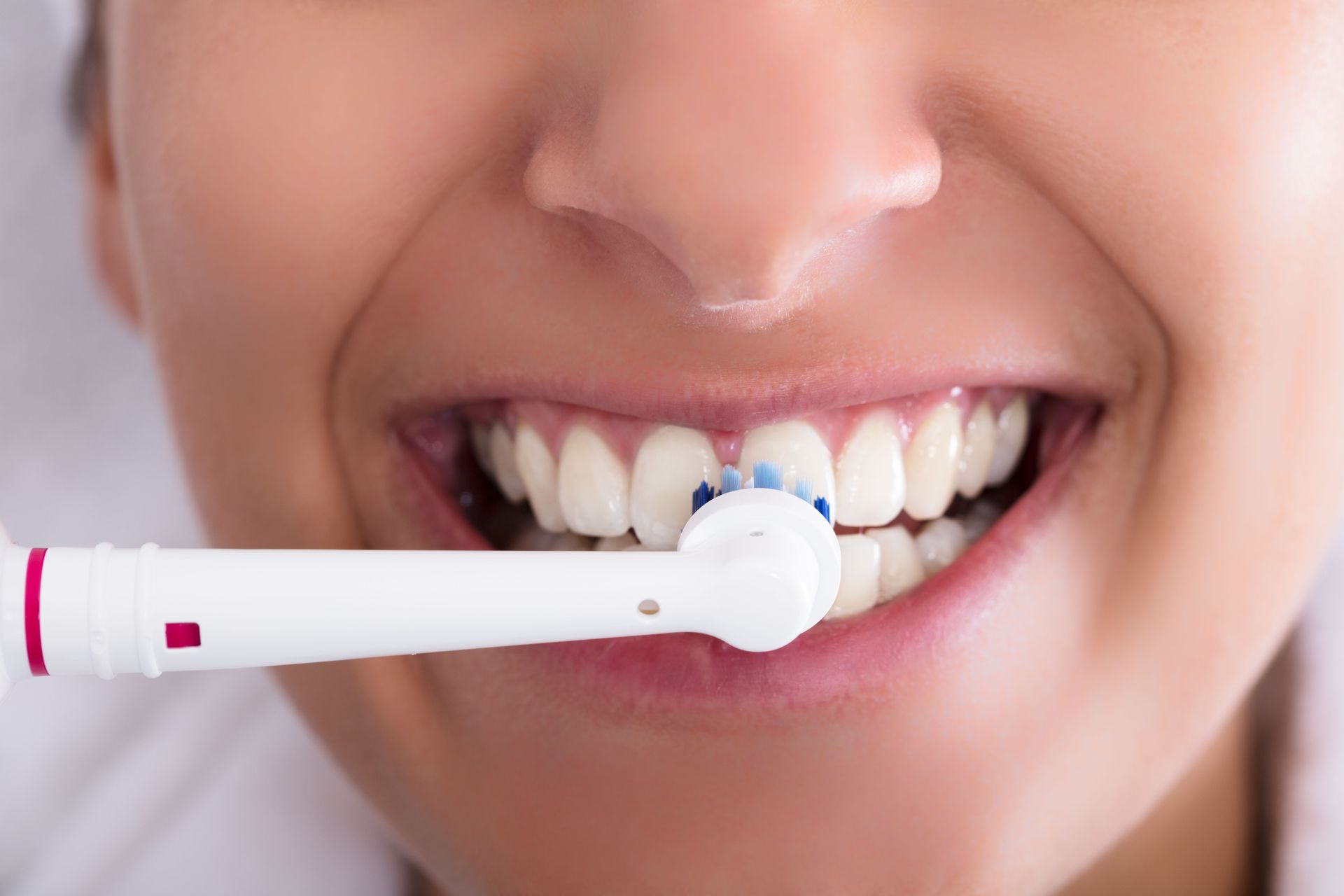 Person brushing teeth with a white electric toothbrush
