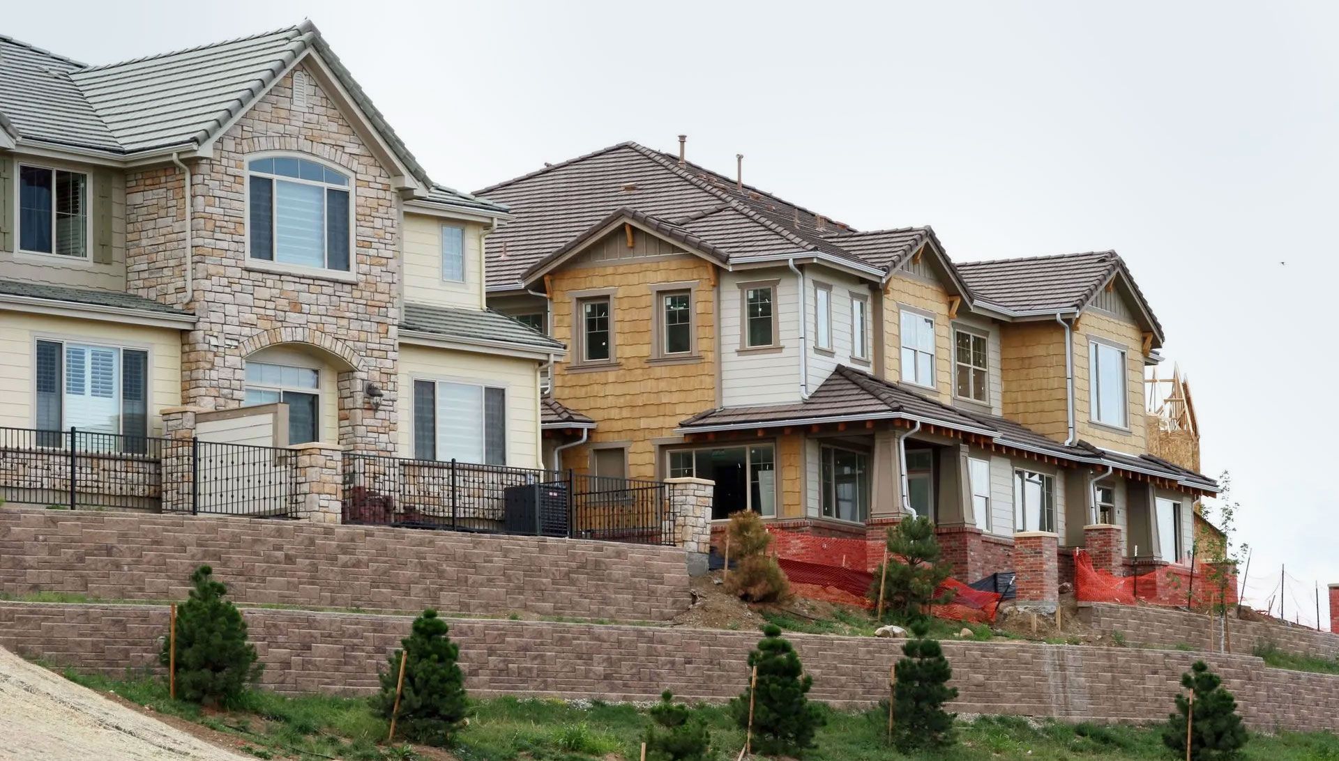 Row of newly built stone and wood townhouses on a sloped hillside with front porches and landscaping