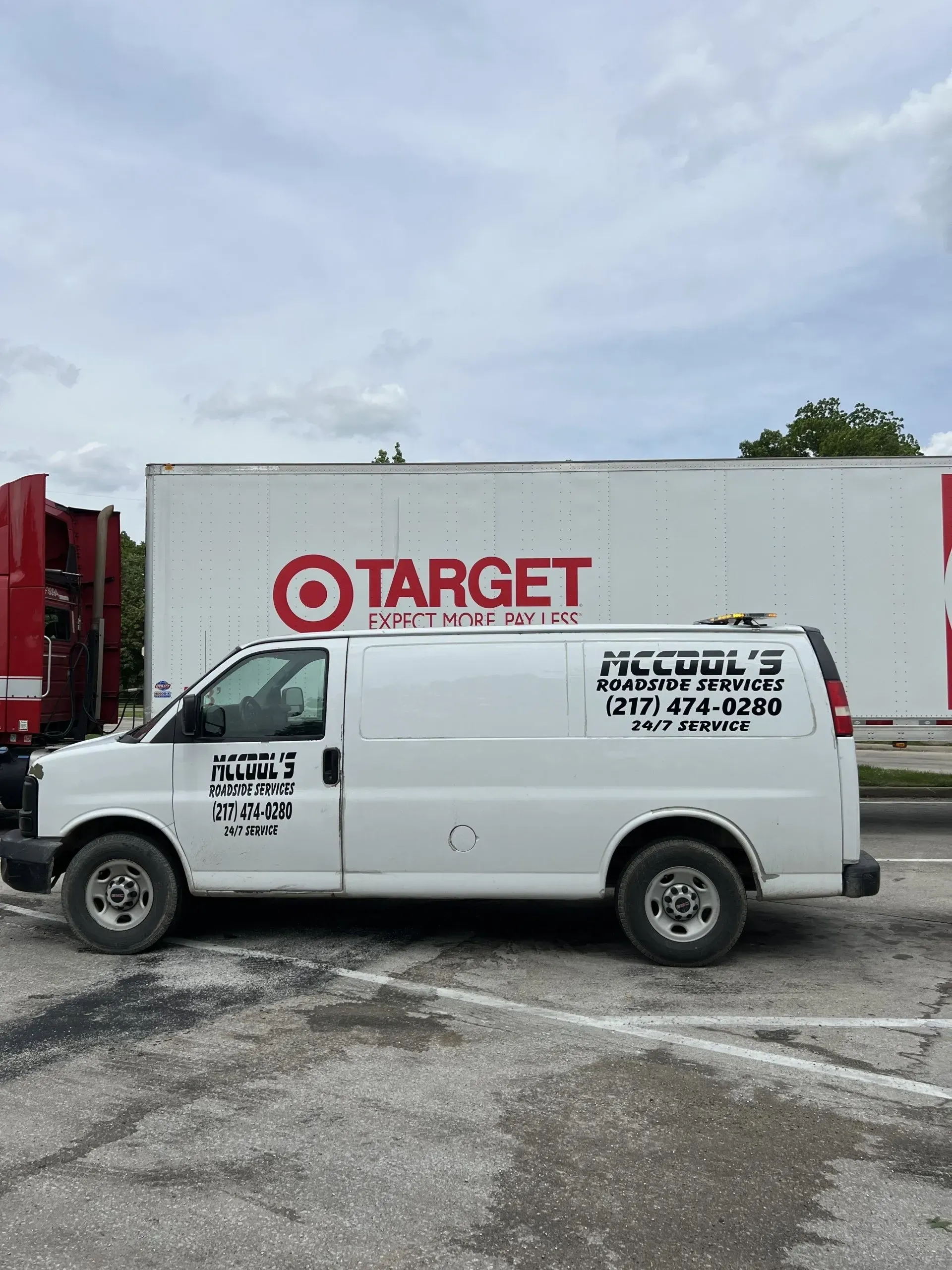 White service van parked in front of a Target truck. McCool's lettering on van. Cloudy sky.