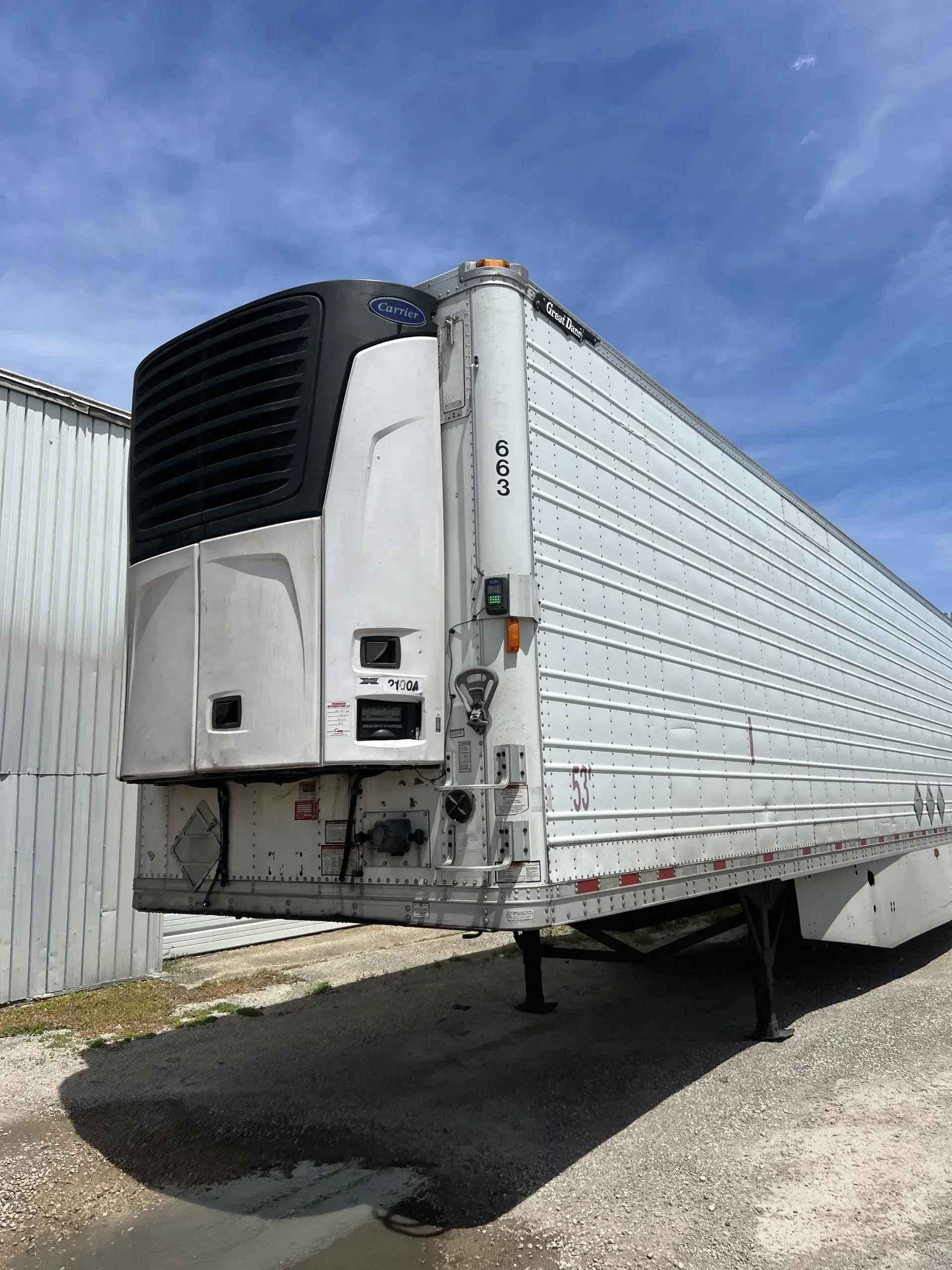 Refrigerated semi-trailer parked outdoors, white with a black cooling unit.
