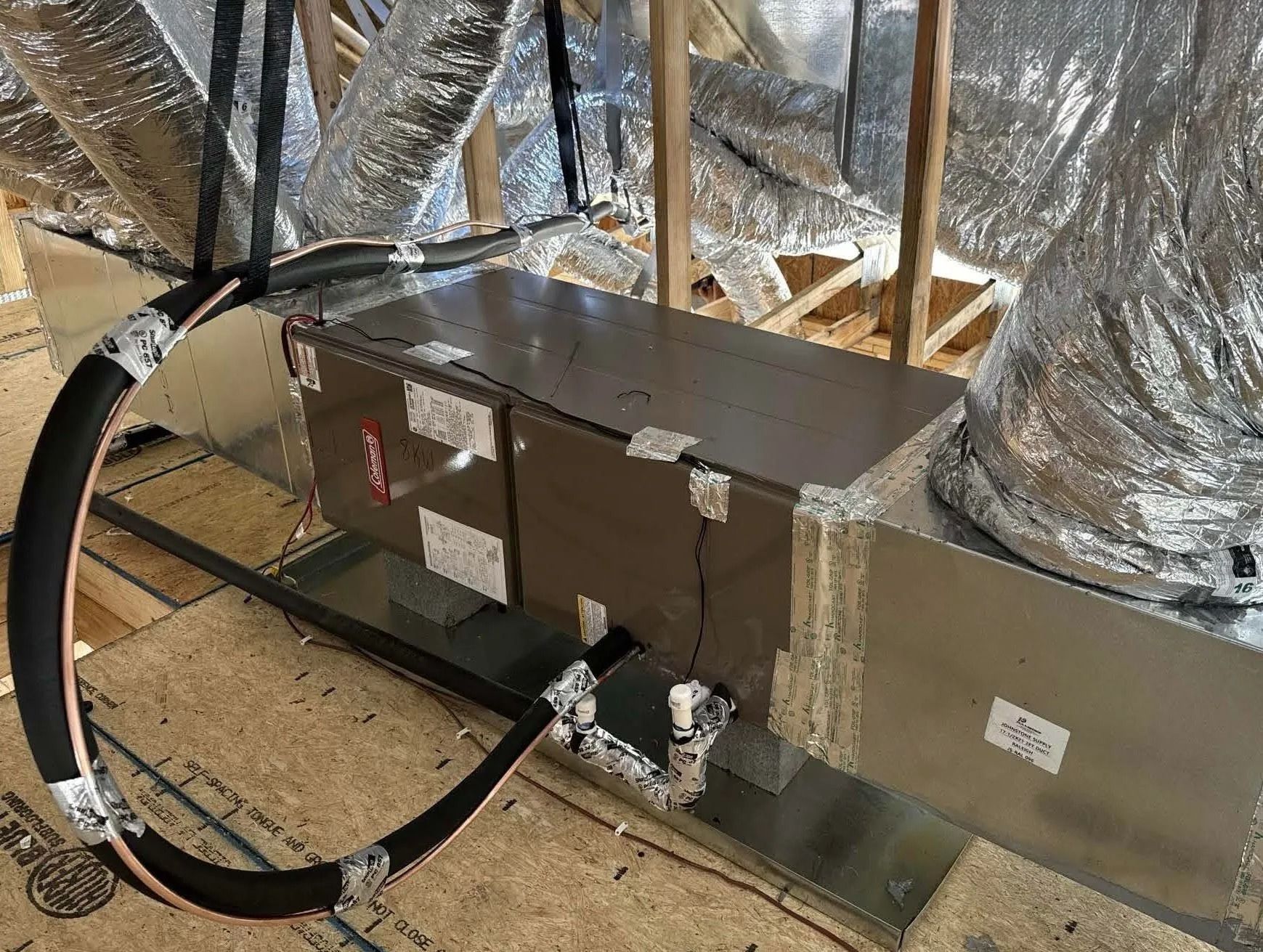 HVAC air handler in an attic, with flexible ducting and metallic insulation.