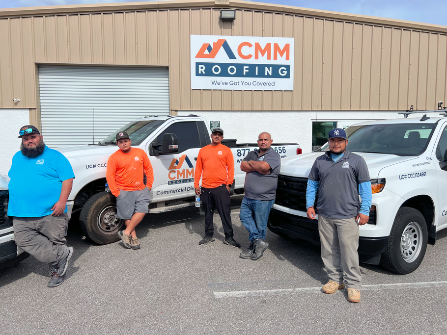 White CMM roofing truck parked on asphalt; business logo and phone number displayed.