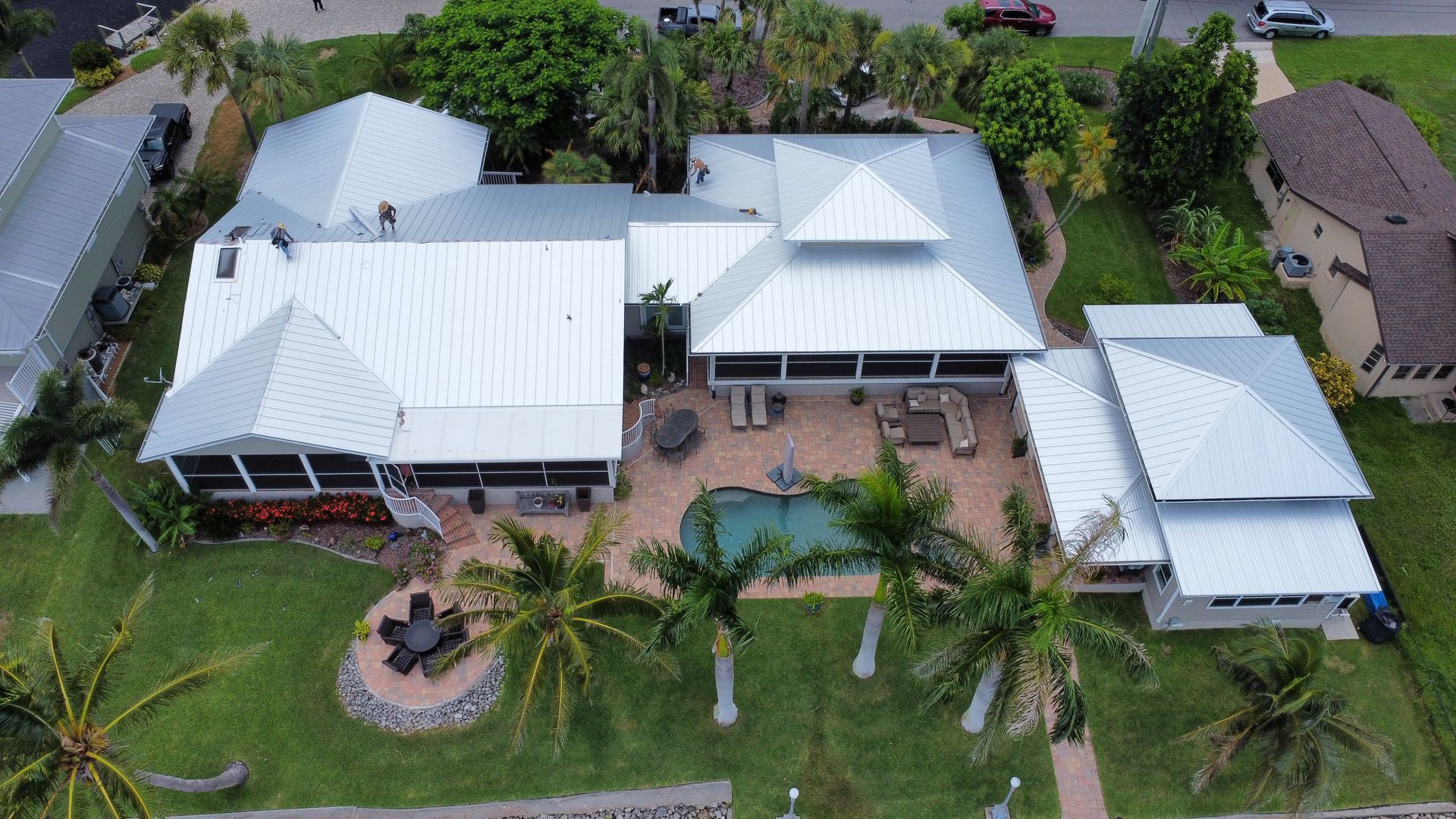 An aerial view of a large house with a pool and palm trees.