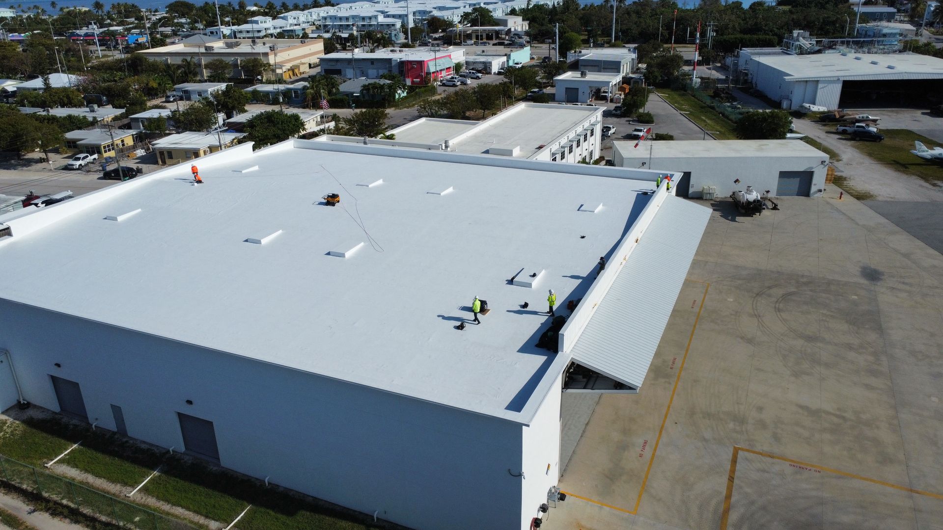 An aerial view of a large white building with workers on the roof.