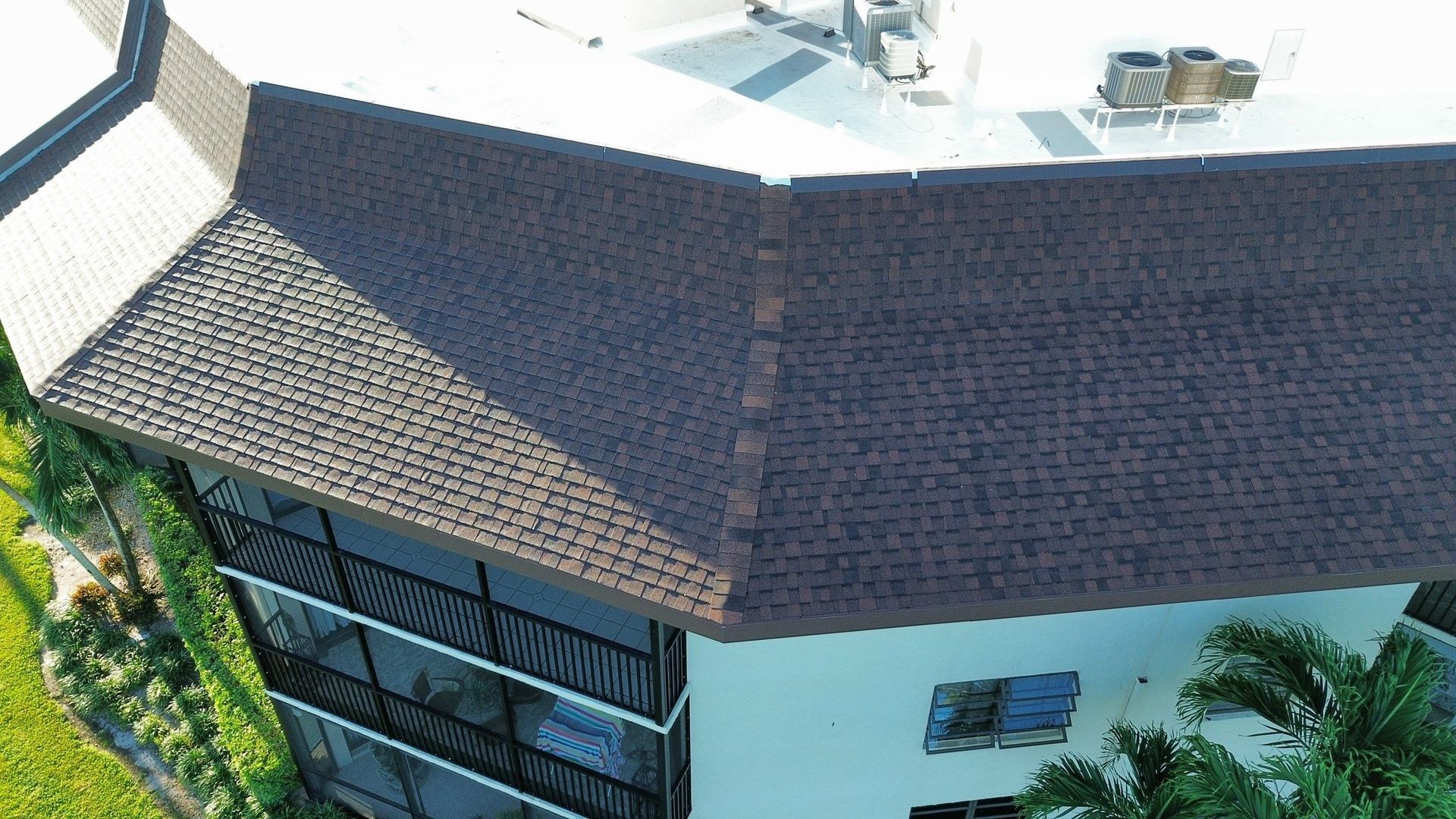 Aerial view of a modern house with a dark roof, large windows, and white exterior walls.