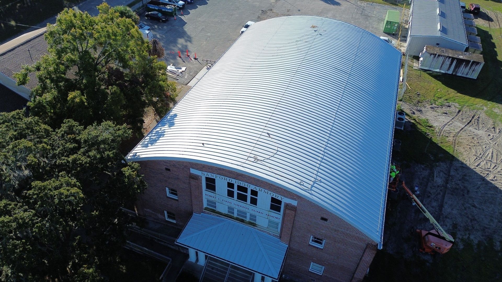 Aerial view of a brick building with a white curved metal roof and concentric patterns