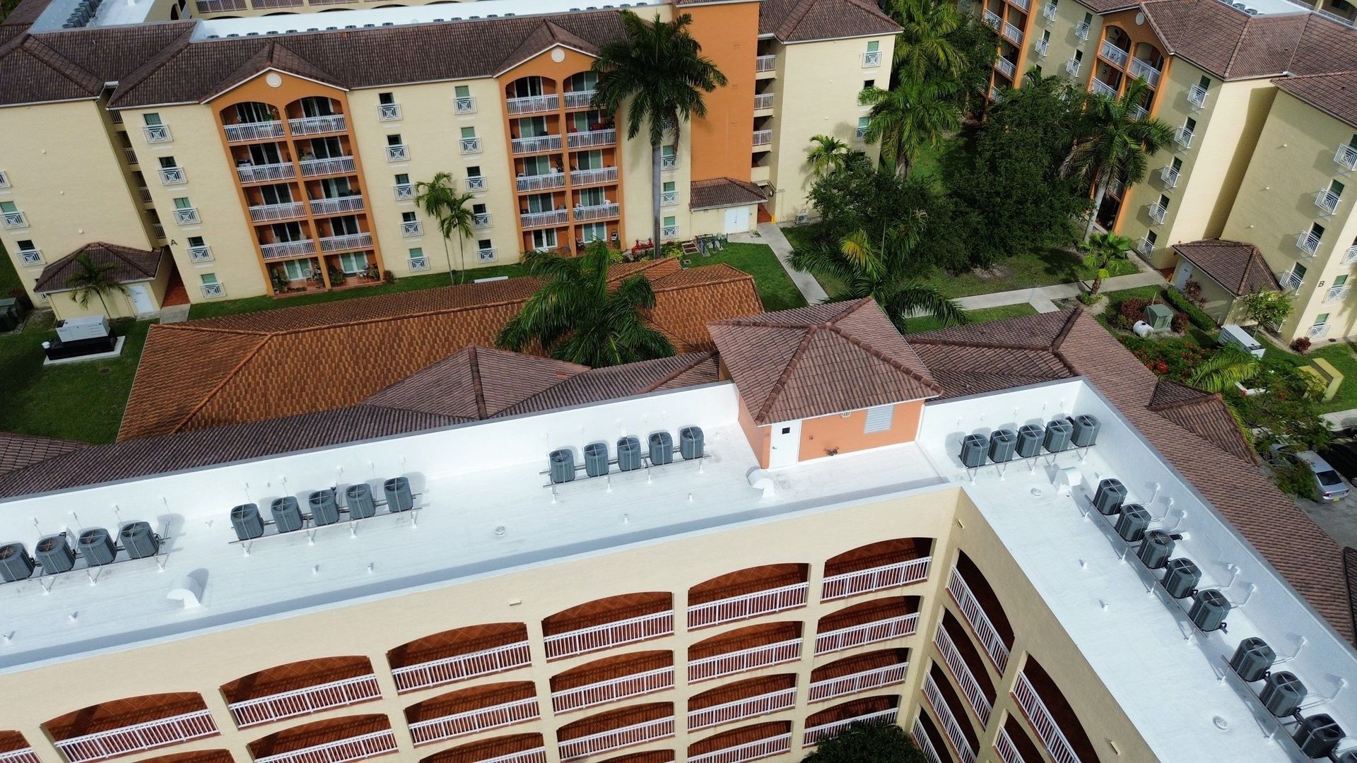 Aerial view of a multi-story apartment complex with red-tiled roofs and a central courtyard